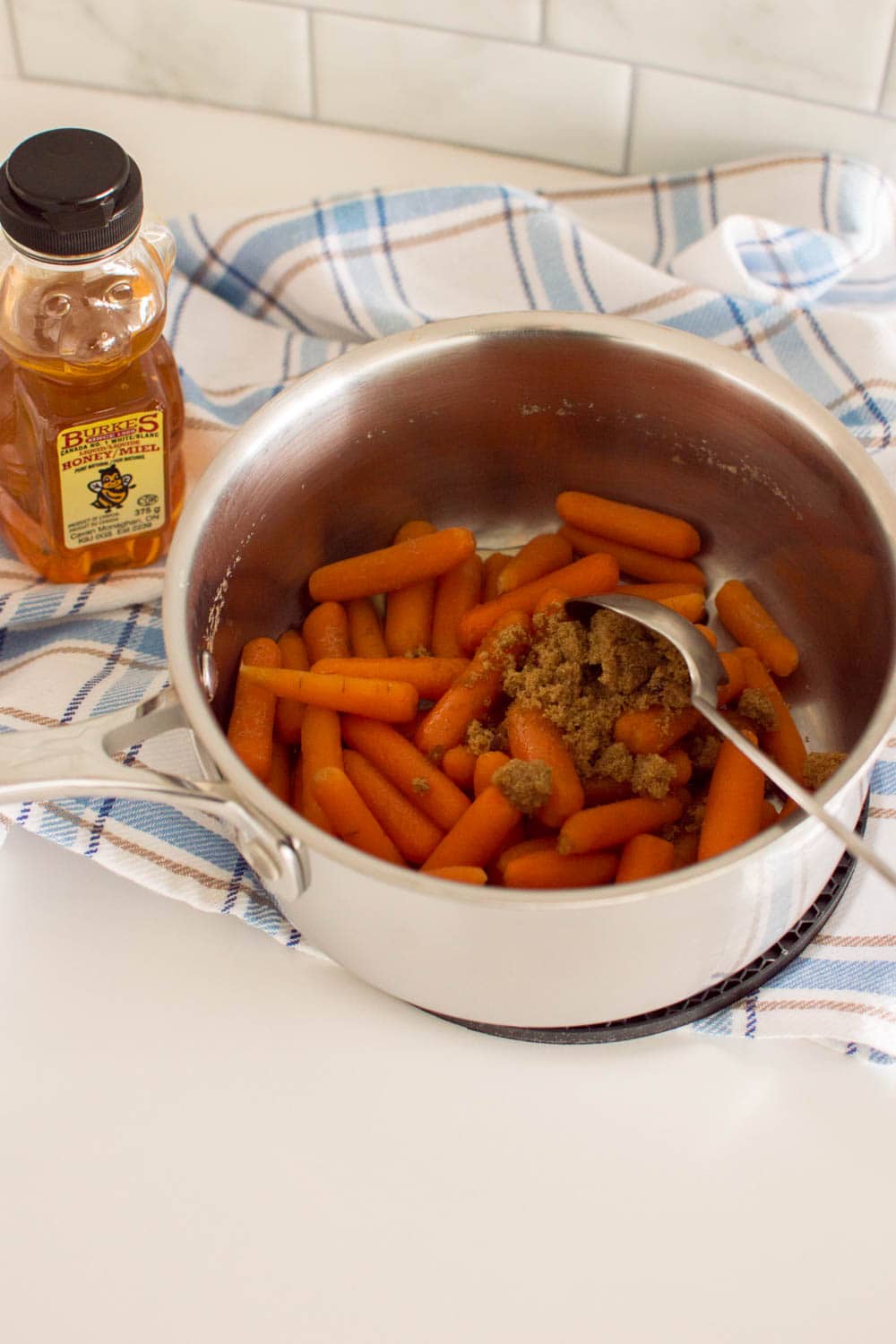 Adding brown sugar and honey into boiled baby carrots