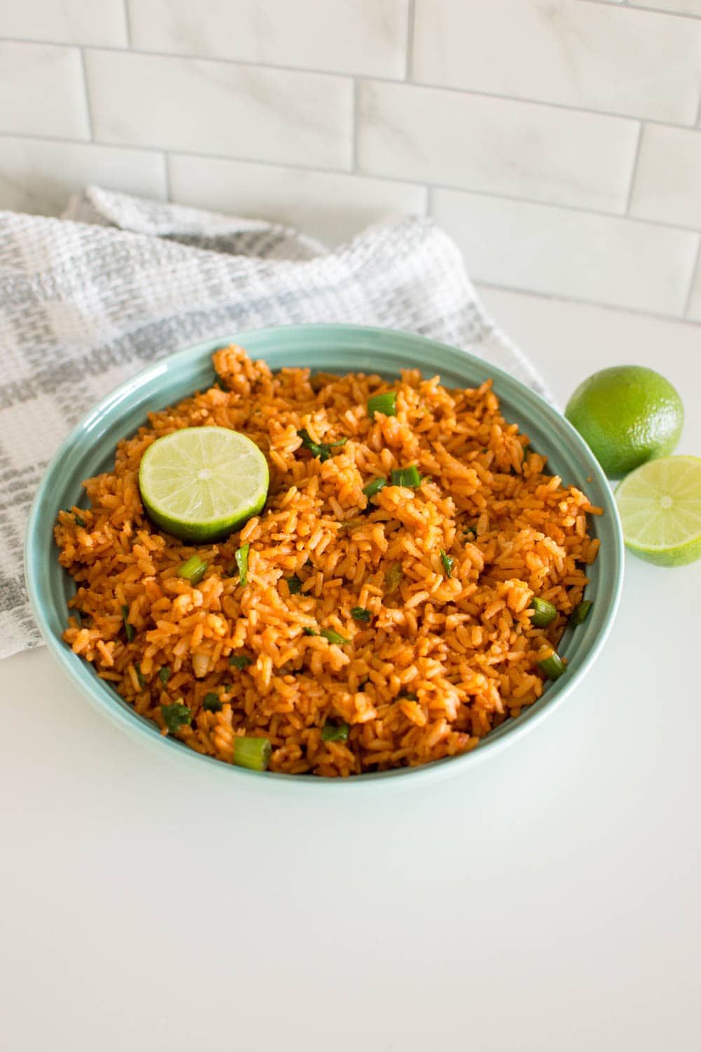 Our recipe for Easy Mexican Rice in a mint green bowl, served with a slice of fresh lime