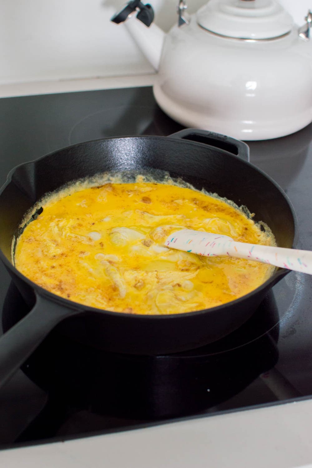 Frying some eggs to make easy scrambled eggs in a black cast iron pan