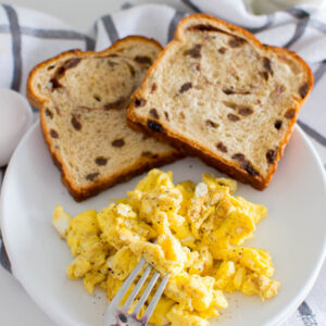 Aerial view of scrambled eggs, homemade and accompanied by raisin bread