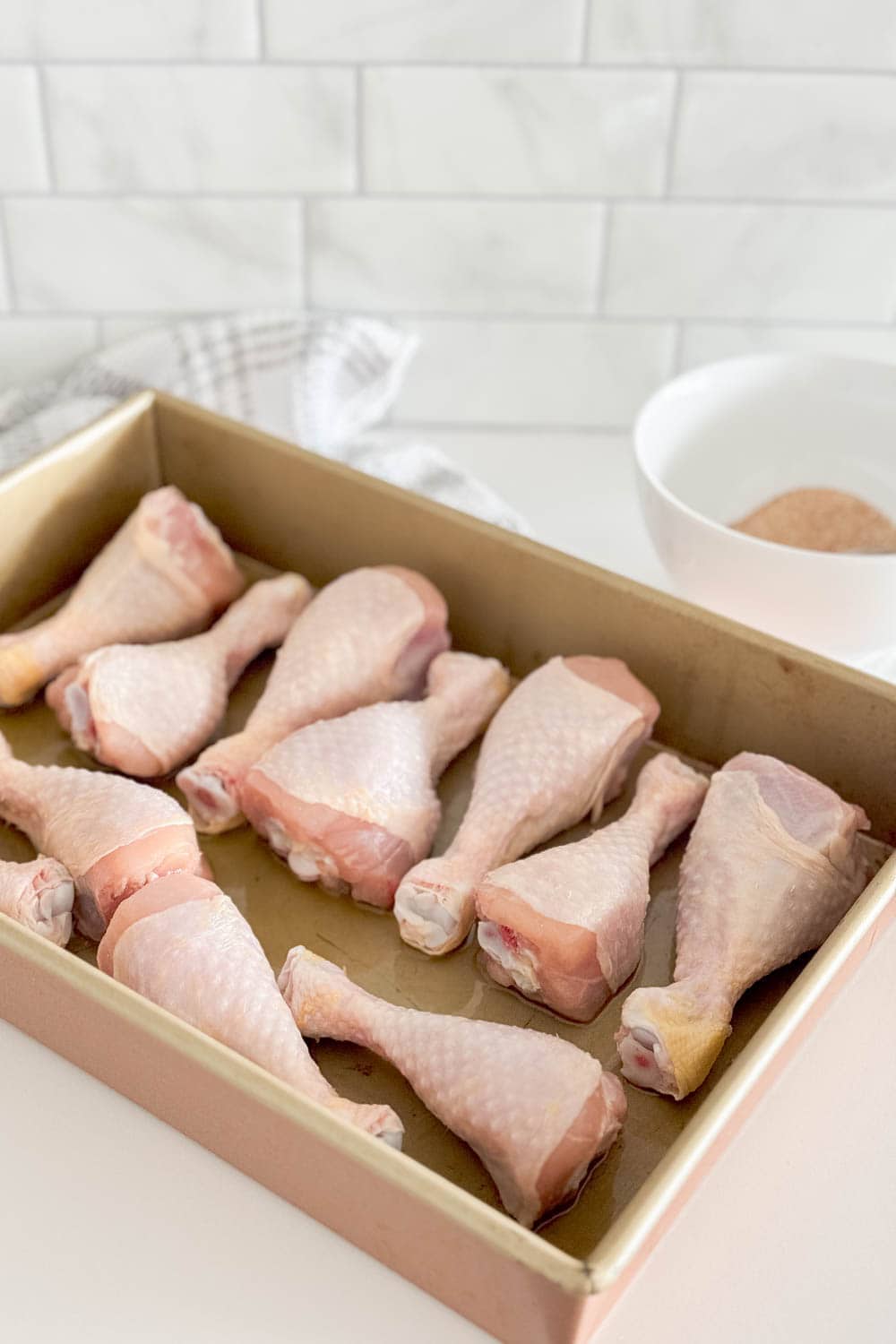 Lining up raw chicken drumsticks in a pan
