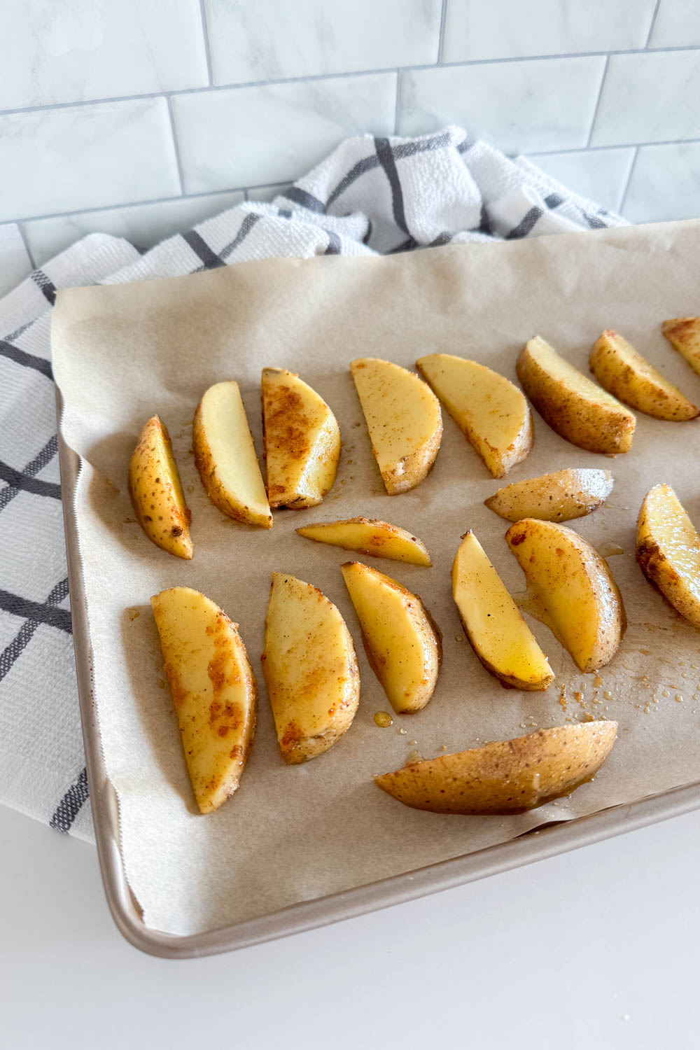 Potato wedges freshly out of the oven on a parchment-lined cookie sheet