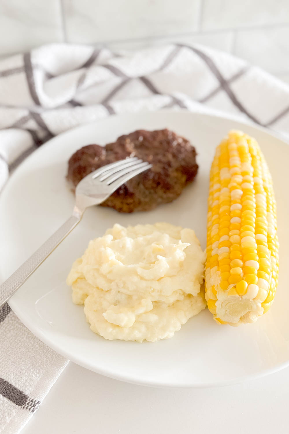 Aerial view of easy mashed potatoes being served as a side with steak and corn