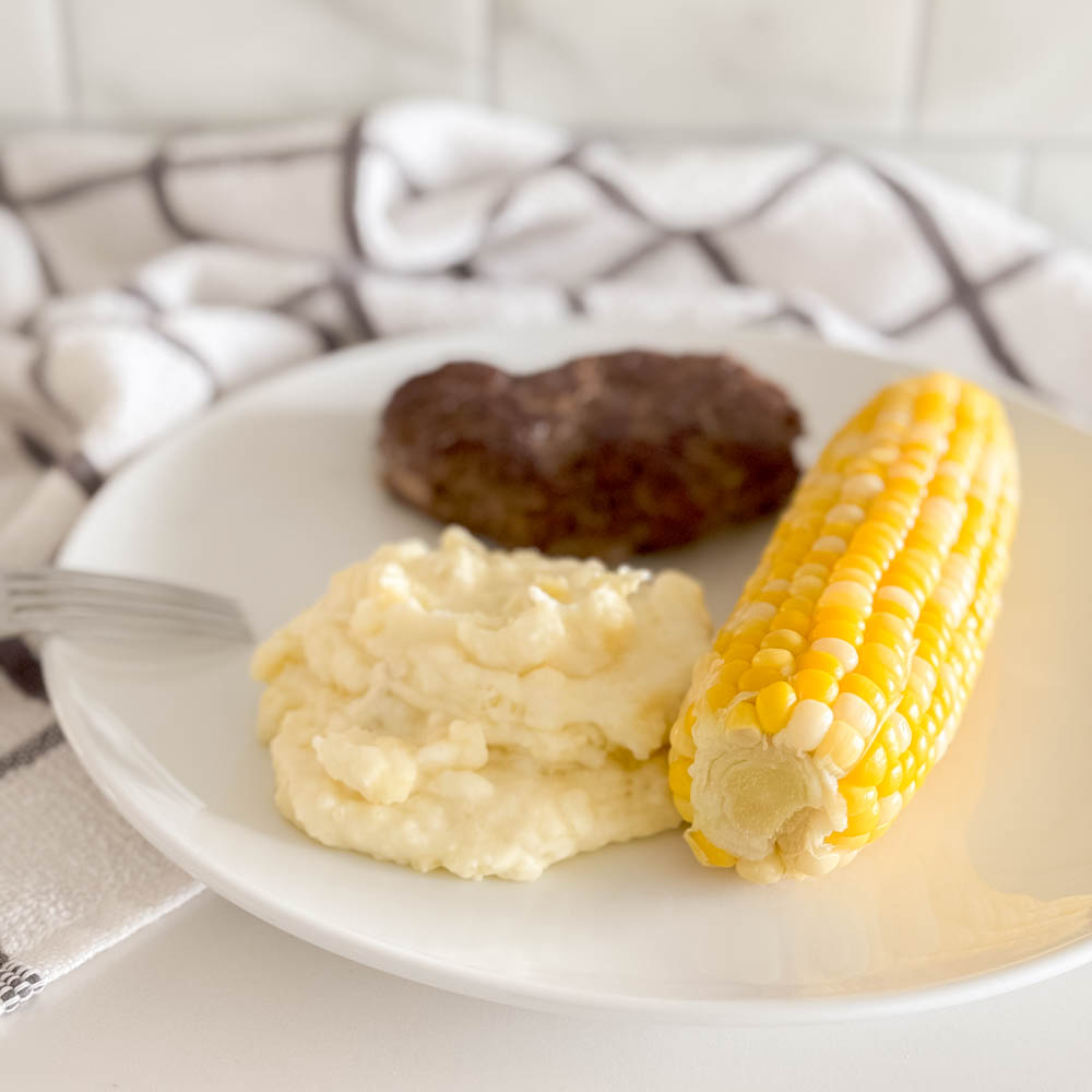 Aerial view of easy mashed potatoes being served as a side with steak and corn