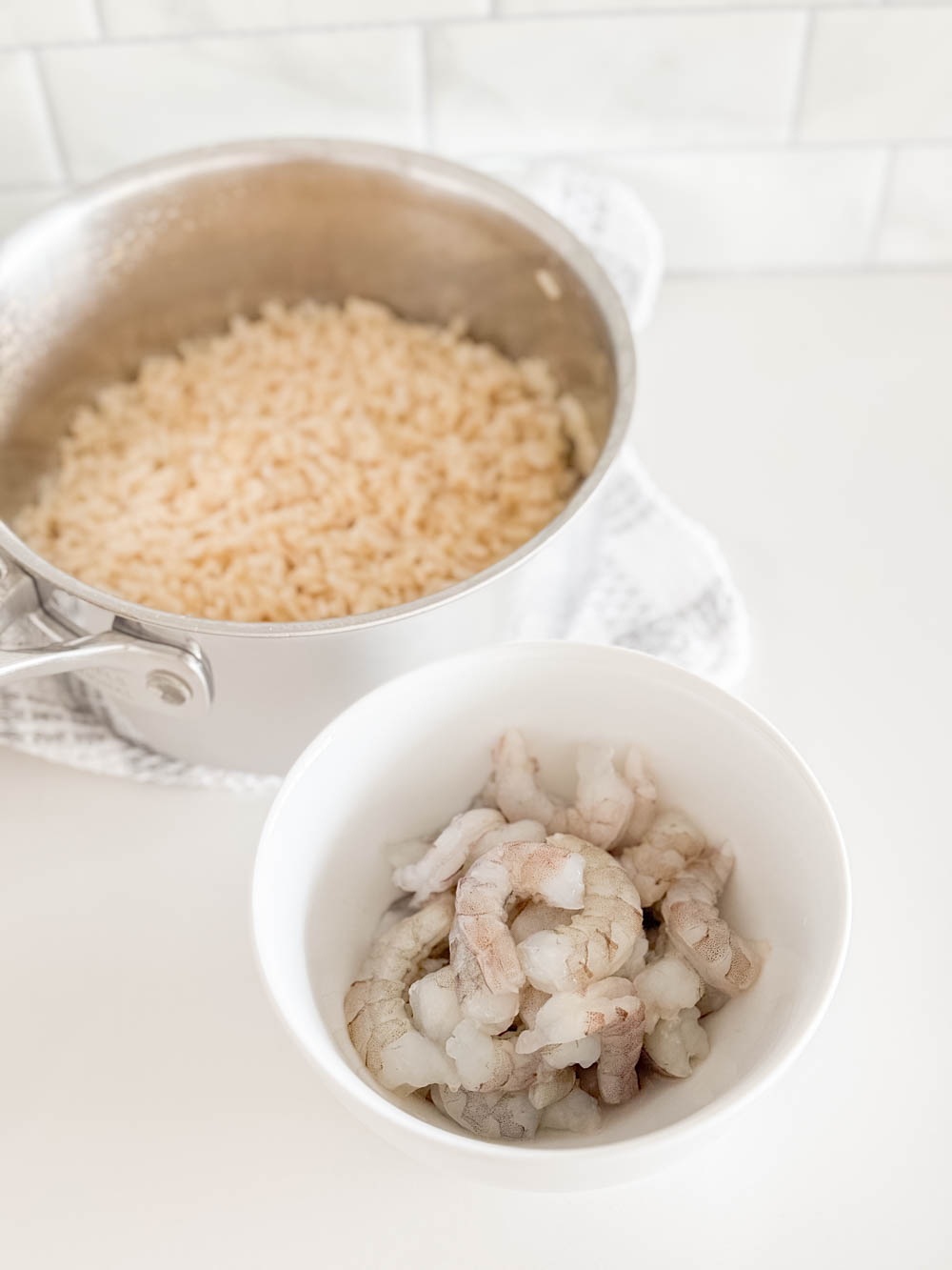 A bowl of raw shrimp and brown rice in a stainless steel pot